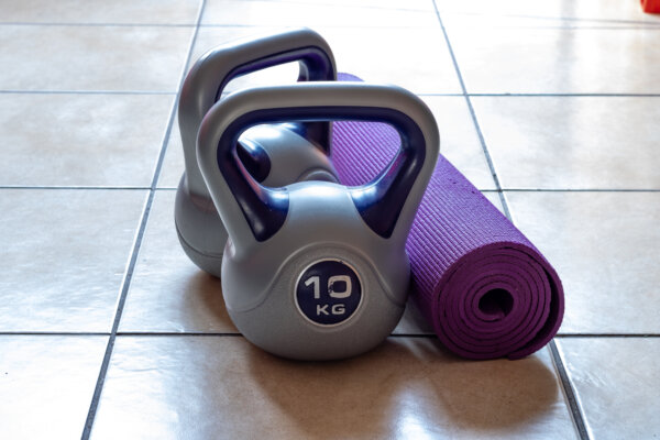 Two 10kg kettlebell weights and purple yoga mat on the floor