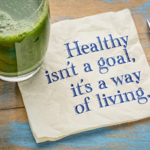 Healthy is not a goal, it is a way of living advice or reminder - handwriting on a napkin with a glass of fresh, green, vegetable juice