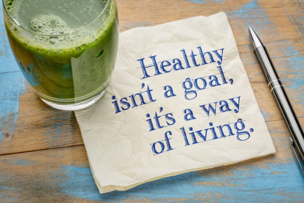 Healthy is not a goal, it is a way of living advice or reminder - handwriting on a napkin with a glass of fresh, green, vegetable juice